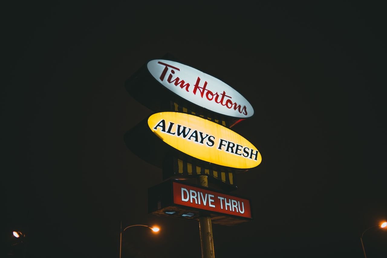 Low angle of signboards with inscriptions against streetlights under dark sky in city at night