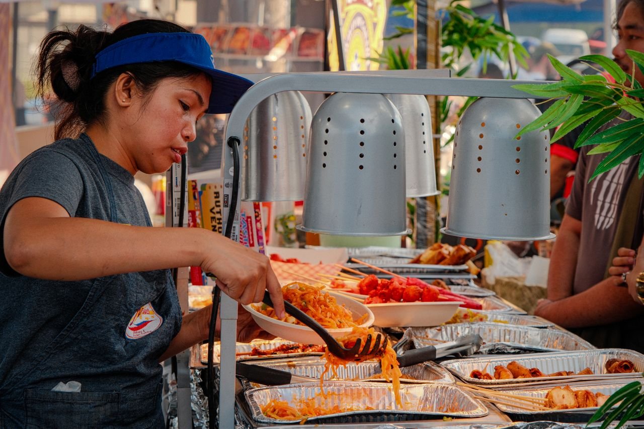 A woman serving vibrant street food at an outdoor market in Toronto, capturing urban culinary culture.